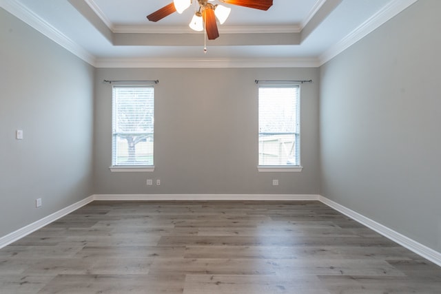 empty room with light wood-type flooring, ceiling fan, a tray ceiling, and a wealth of natural light