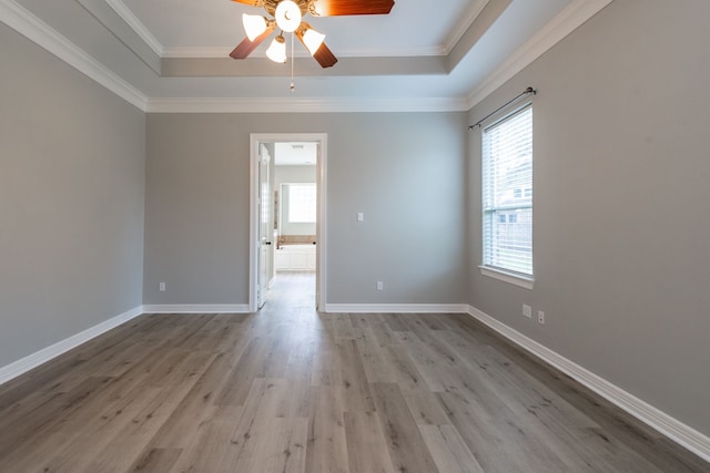 unfurnished room featuring light wood-type flooring, ceiling fan, a tray ceiling, and crown molding