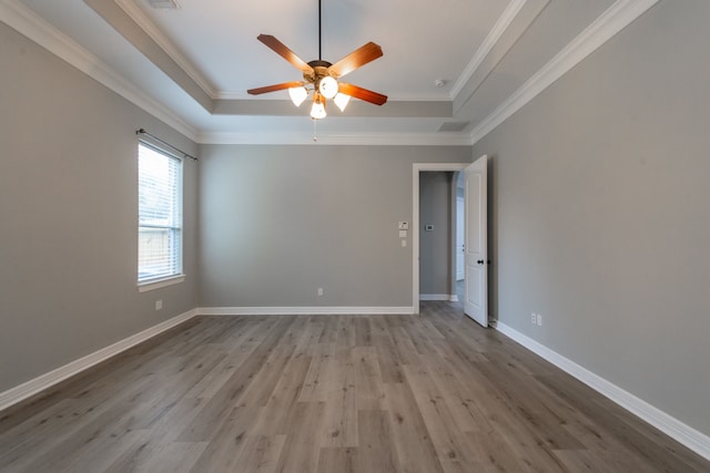 unfurnished room featuring light hardwood / wood-style floors, a raised ceiling, ornamental molding, and ceiling fan