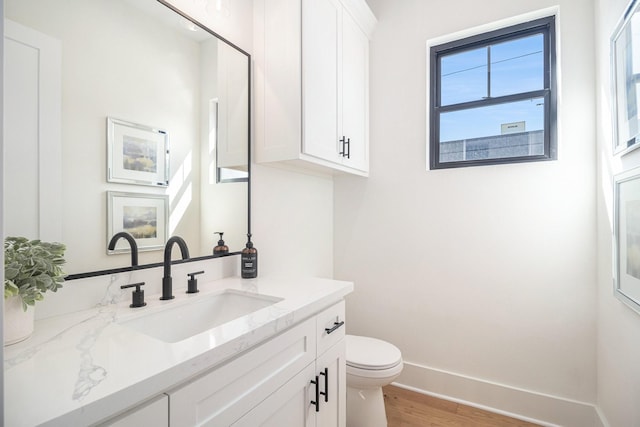 bathroom with wood-type flooring, vanity, and toilet