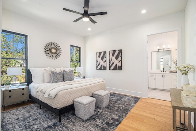 bedroom with multiple windows, light wood-type flooring, ensuite bath, and ceiling fan