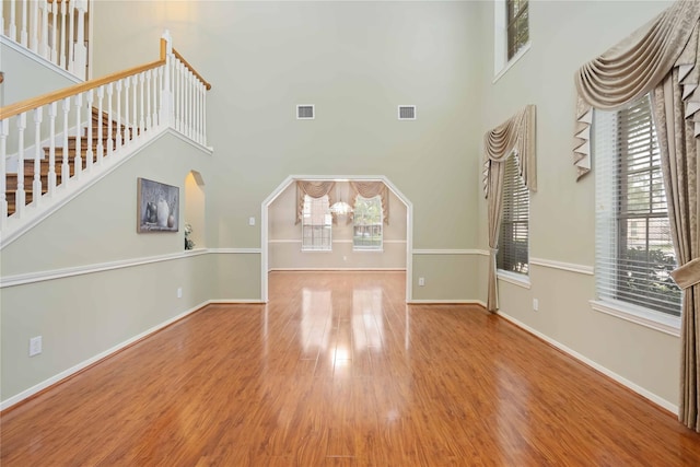 unfurnished living room with light wood-type flooring, plenty of natural light, and a high ceiling