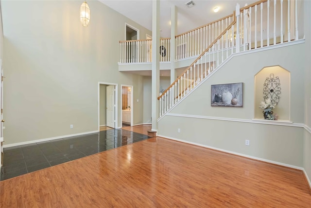 unfurnished living room with dark tile patterned flooring and a towering ceiling