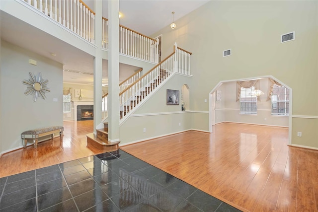 foyer featuring a towering ceiling, a tile fireplace, and hardwood / wood-style floors