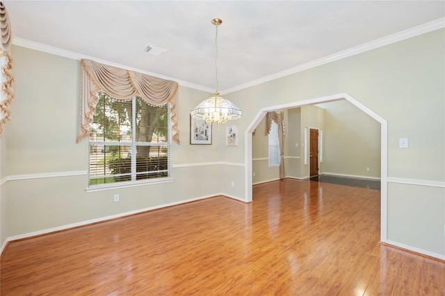 unfurnished dining area featuring an inviting chandelier, ornamental molding, and hardwood / wood-style floors