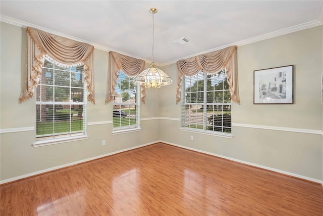 spare room featuring wood-type flooring, a wealth of natural light, and an inviting chandelier