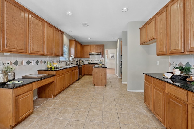 kitchen with decorative backsplash, dark stone countertops, dishwasher, a kitchen island, and sink