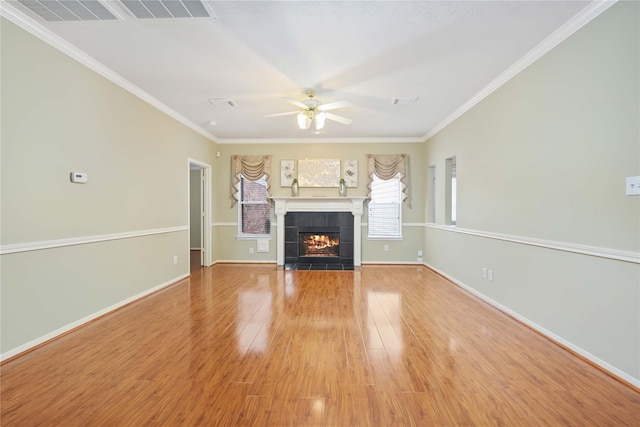 unfurnished living room with hardwood / wood-style flooring, ceiling fan, ornamental molding, and a tiled fireplace