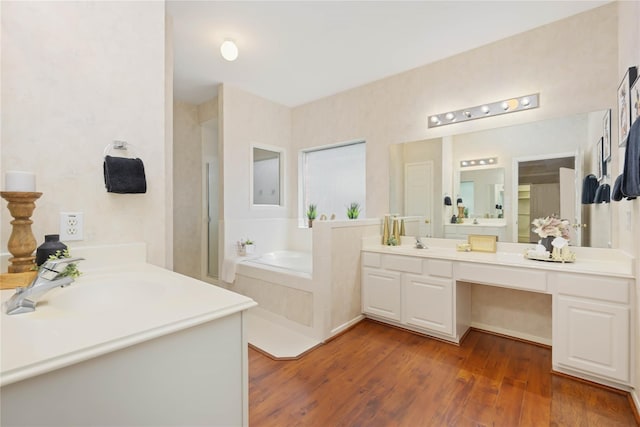 bathroom with tiled bath, vanity, and hardwood / wood-style flooring