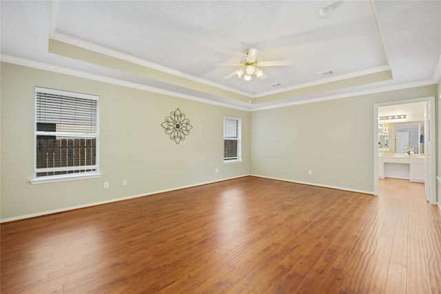 spare room with ceiling fan, a tray ceiling, ornamental molding, and hardwood / wood-style flooring