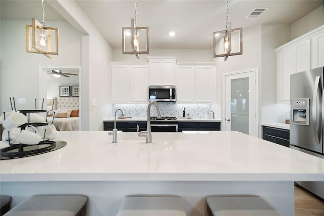 kitchen with pendant lighting, a kitchen breakfast bar, white cabinets, and appliances with stainless steel finishes