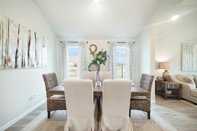 dining space with light hardwood / wood-style flooring, vaulted ceiling, and a wealth of natural light