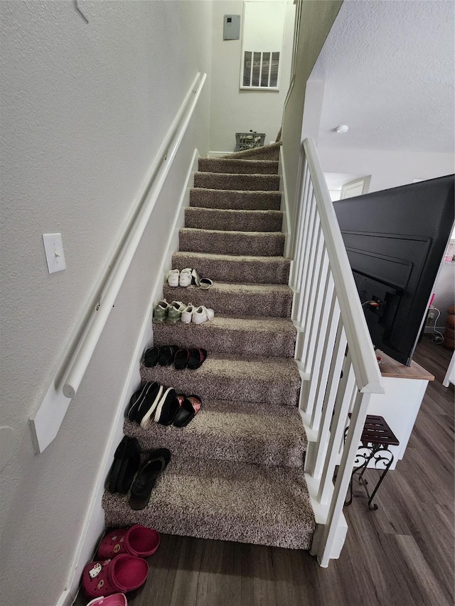 stairs featuring wood-type flooring and a textured ceiling