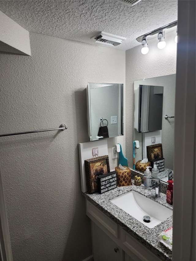 bathroom with rail lighting, vanity, and a textured ceiling