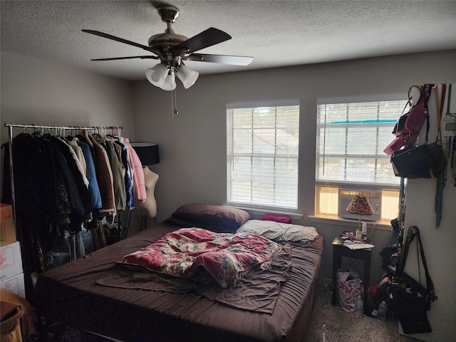 carpeted bedroom featuring ceiling fan and a textured ceiling