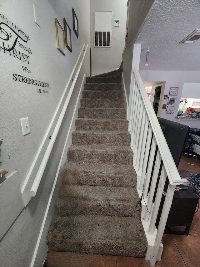 stairway featuring tile patterned flooring and a textured ceiling