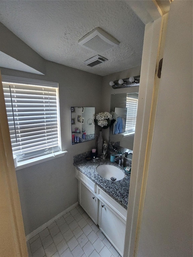 bathroom with tile patterned floors, vanity, a healthy amount of sunlight, and a textured ceiling