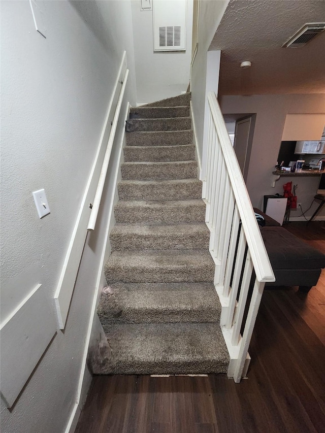 stairs featuring a textured ceiling and hardwood / wood-style flooring