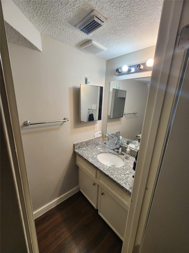 bathroom with vanity, a textured ceiling, and hardwood / wood-style flooring