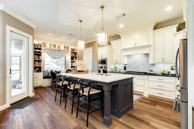 kitchen featuring pendant lighting, white cabinetry, an island with sink, sink, and a kitchen bar