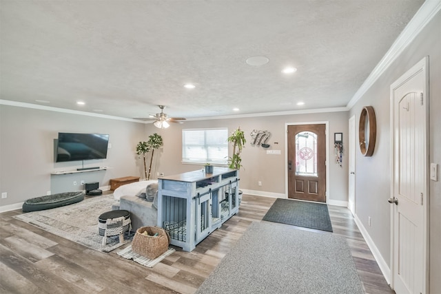 entrance foyer with hardwood / wood-style floors, ceiling fan, and ornamental molding