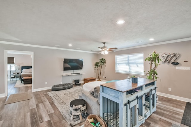 living room featuring ceiling fan, light hardwood / wood-style flooring, a textured ceiling, and ornamental molding