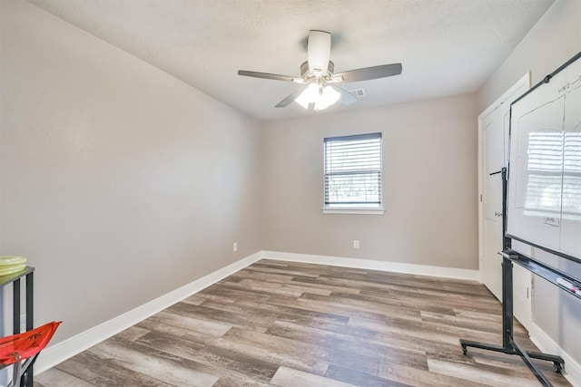 empty room featuring ceiling fan, wood-type flooring, and a textured ceiling