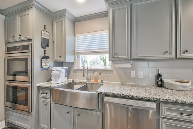 kitchen featuring sink, stainless steel appliances, tasteful backsplash, light stone counters, and gray cabinets