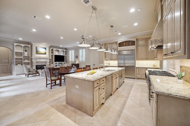 kitchen featuring pendant lighting, sink, a large island with sink, light stone counters, and stainless steel appliances