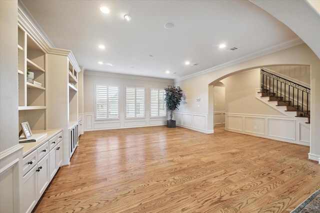 unfurnished living room featuring light hardwood / wood-style flooring, built in features, and ornamental molding