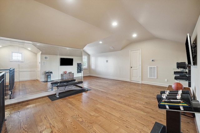 exercise room with light hardwood / wood-style floors and vaulted ceiling