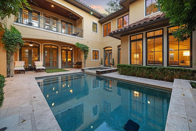 pool at dusk with an in ground hot tub and a patio area