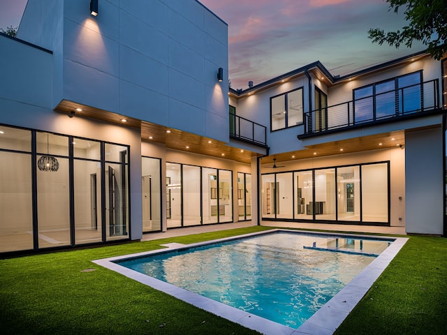 pool at dusk featuring a lawn