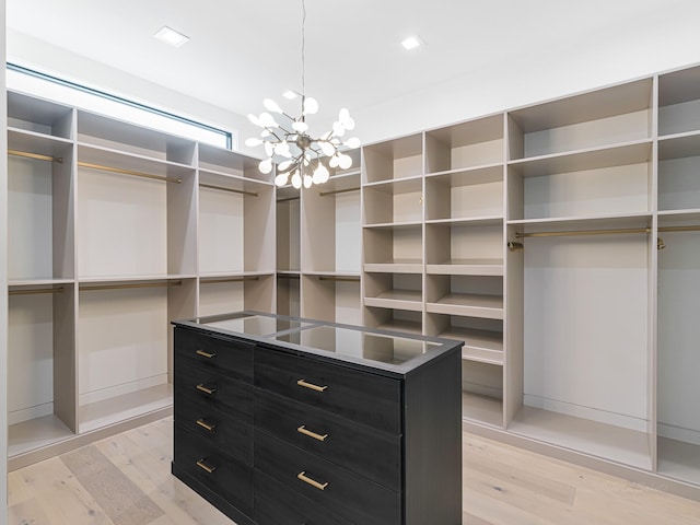 spacious closet with light hardwood / wood-style flooring and a chandelier