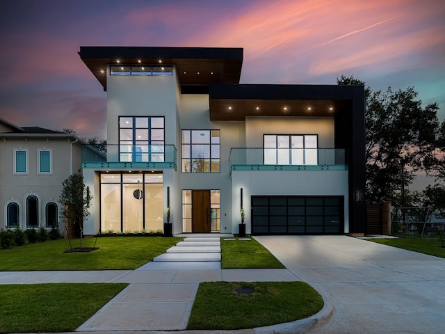 modern home featuring a lawn, a balcony, and a garage