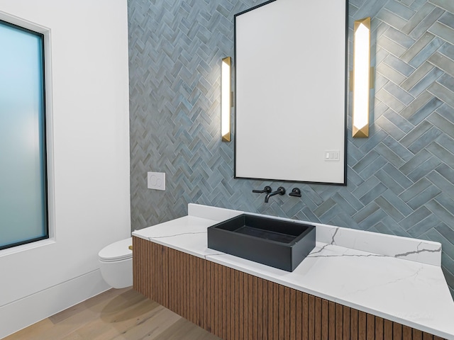 bathroom featuring decorative backsplash, wood-type flooring, vanity, and toilet