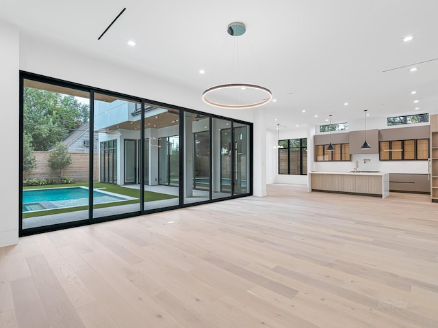 unfurnished living room featuring light wood-type flooring, a wealth of natural light, and sink