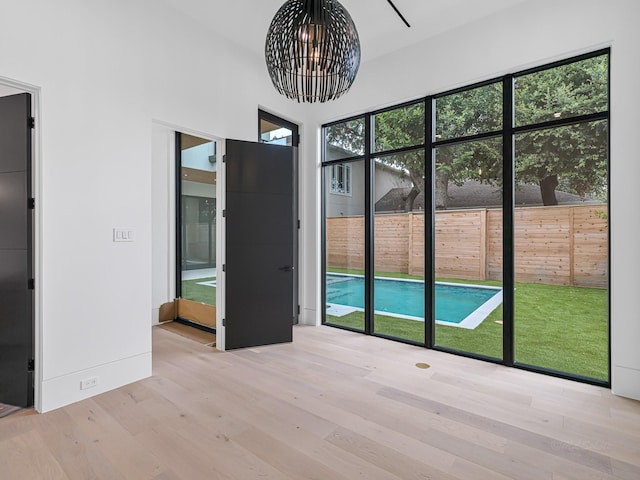 interior space featuring plenty of natural light, light hardwood / wood-style floors, a high ceiling, and an inviting chandelier