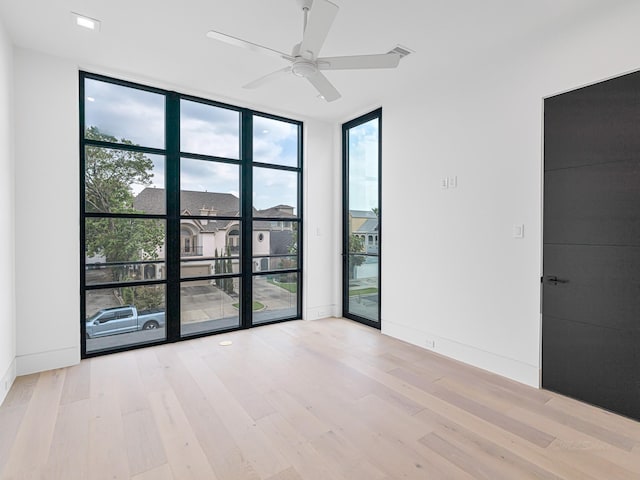 unfurnished room featuring ceiling fan, floor to ceiling windows, and light hardwood / wood-style flooring