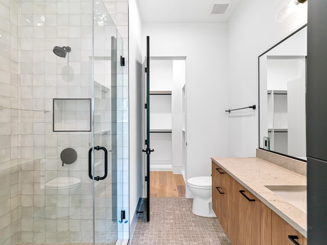 bathroom featuring toilet, vanity, tile patterned floors, and an enclosed shower