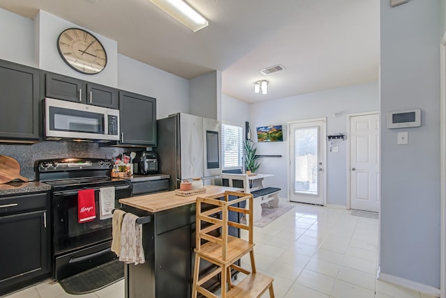 kitchen featuring backsplash, light tile patterned floors, and stainless steel appliances