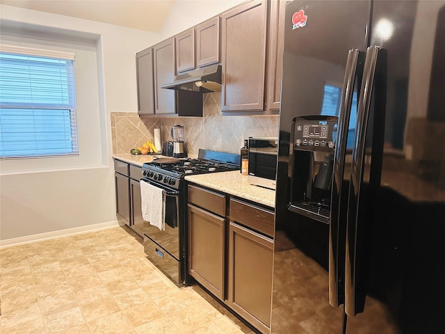 kitchen with decorative backsplash, stainless steel refrigerator with ice dispenser, light stone countertops, black gas range oven, and vaulted ceiling