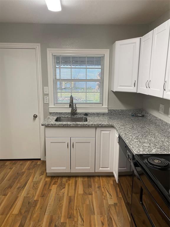 kitchen with light stone countertops, dark hardwood / wood-style flooring, black appliances, sink, and white cabinets