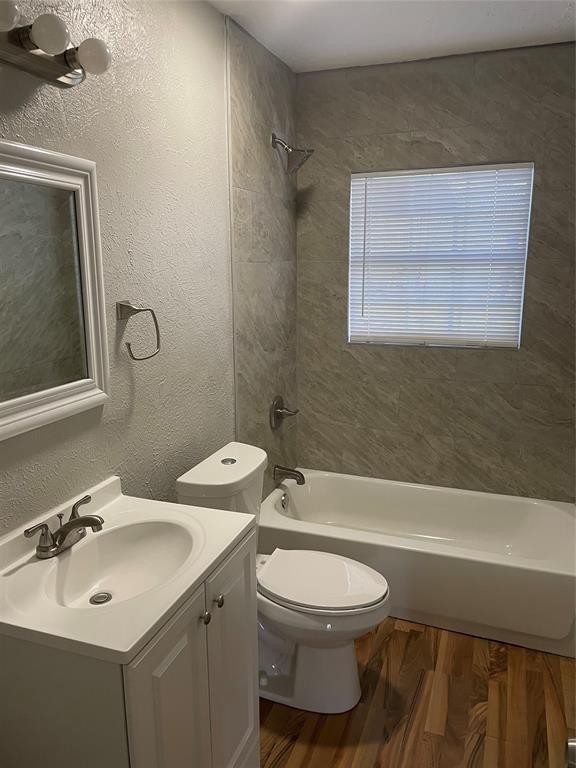 full bathroom with vanity, hardwood / wood-style floors, tiled shower / bath combo, and toilet