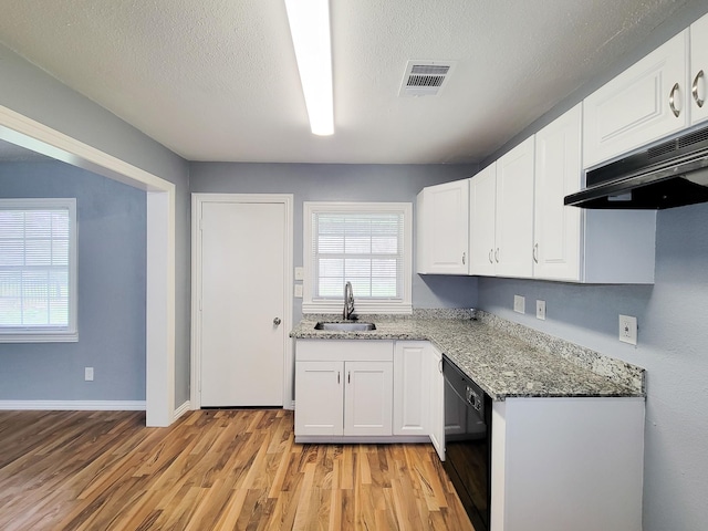 kitchen featuring white cabinetry, black dishwasher, dark stone countertops, sink, and light wood-type flooring