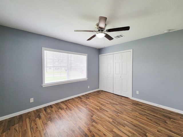 unfurnished bedroom featuring ceiling fan, wood-type flooring, and a closet