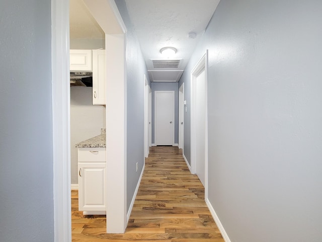 corridor featuring light hardwood / wood-style floors and a textured ceiling