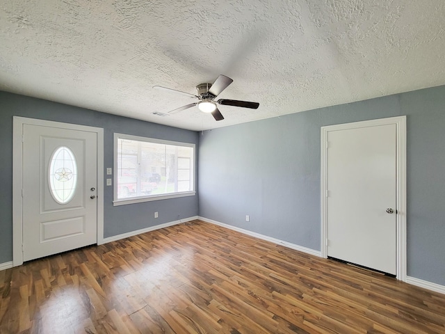 entryway with dark wood-type flooring, ceiling fan, and a textured ceiling