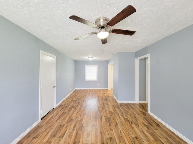 spare room with ceiling fan, a textured ceiling, and light wood-type flooring