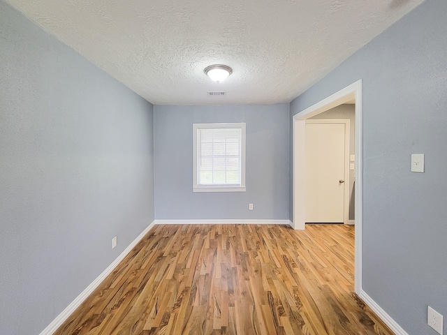 spare room featuring a textured ceiling and light hardwood / wood-style flooring